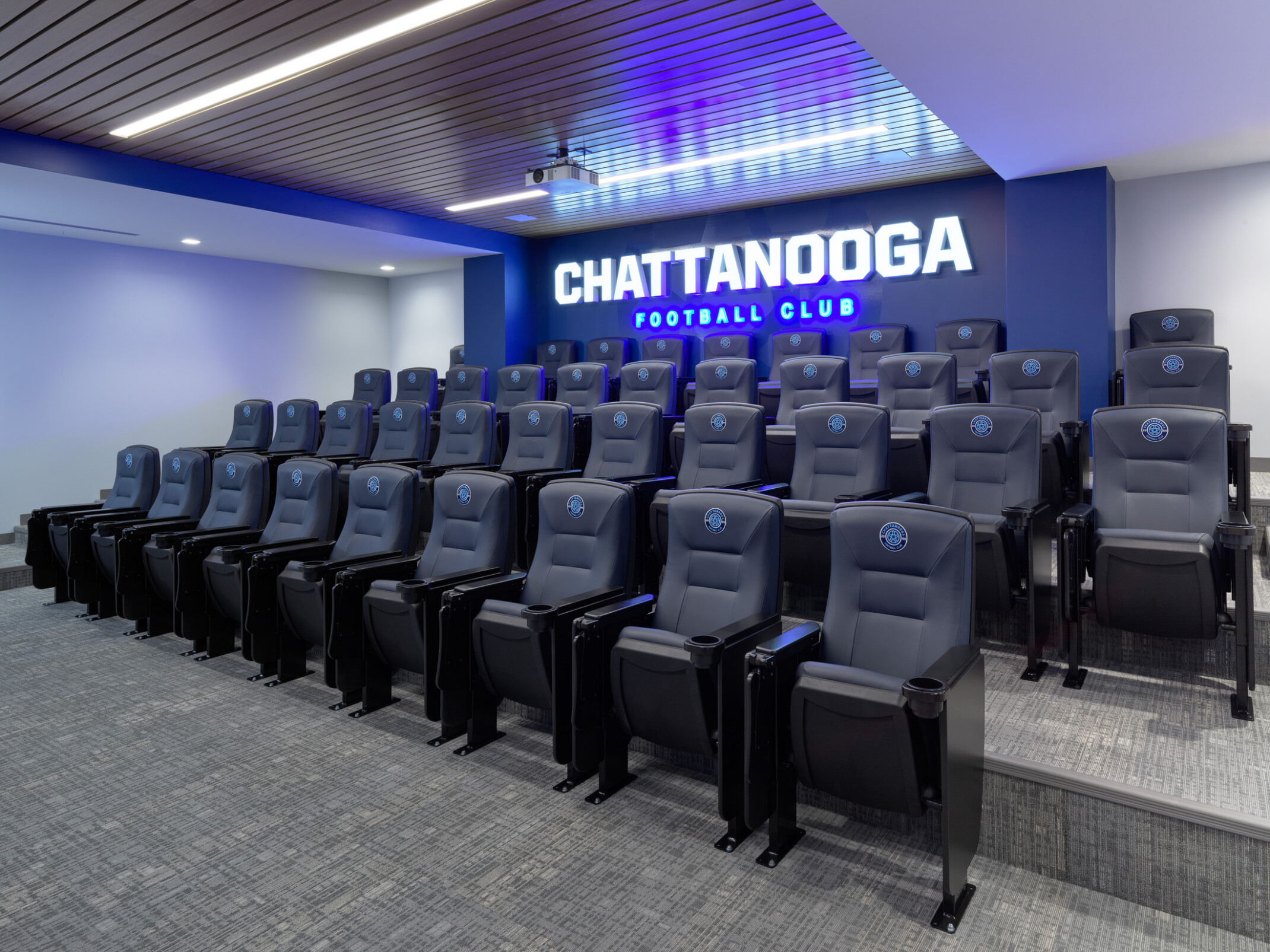 Tiered theater-style presentation room with branded seating and an illuminated “CHATTANOOGA FOOTBALL CLUB” sign on the back wall.