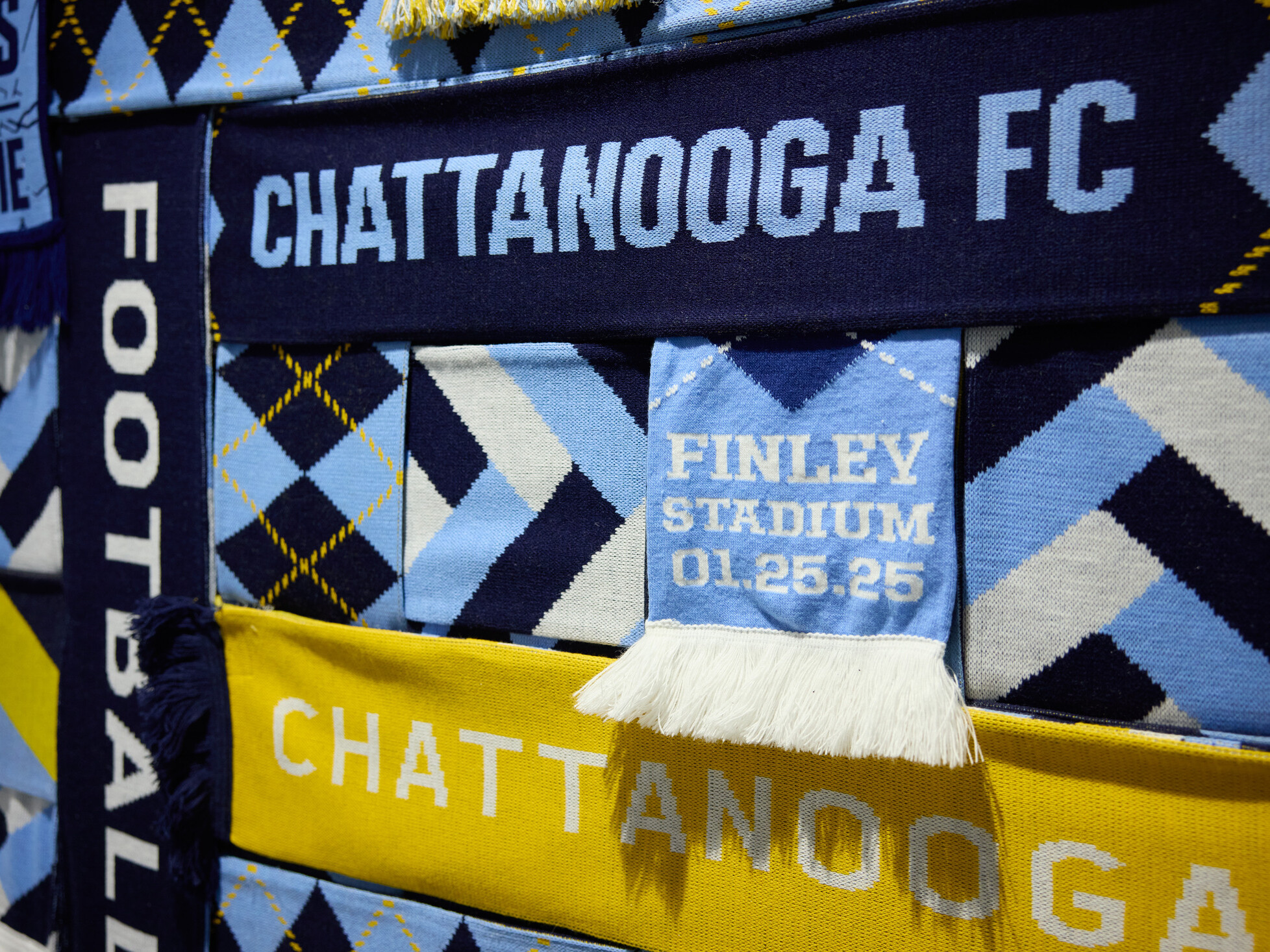 Close-up of a Chattanooga Football Club textile wall display featuring team scarves, geometric patterns, and club-related text including “Chattanooga FC”
