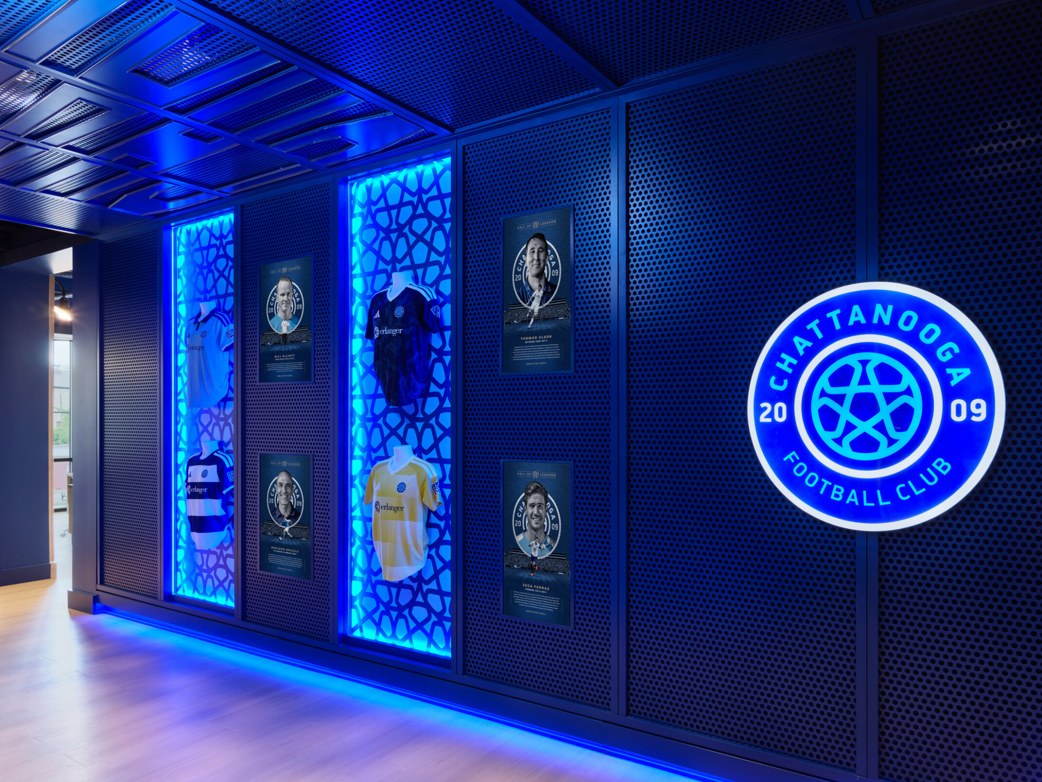 Chattanooga Football Club display wall featuring illuminated team jerseys, player recognition plaques, and a glowing club logo, all highlighted by blue accent lighting.