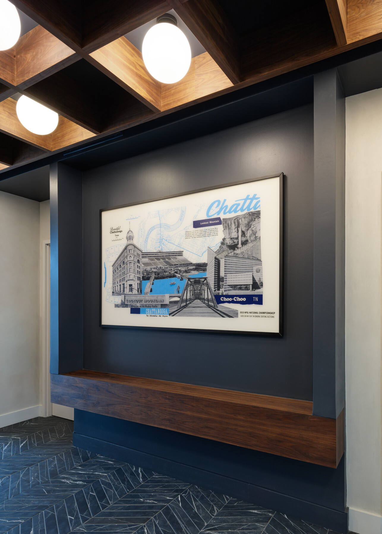 amed Chattanooga-themed artwork displayed on a dark accent wall with wood trim, geometric ceiling details, and patterned tile flooring.
