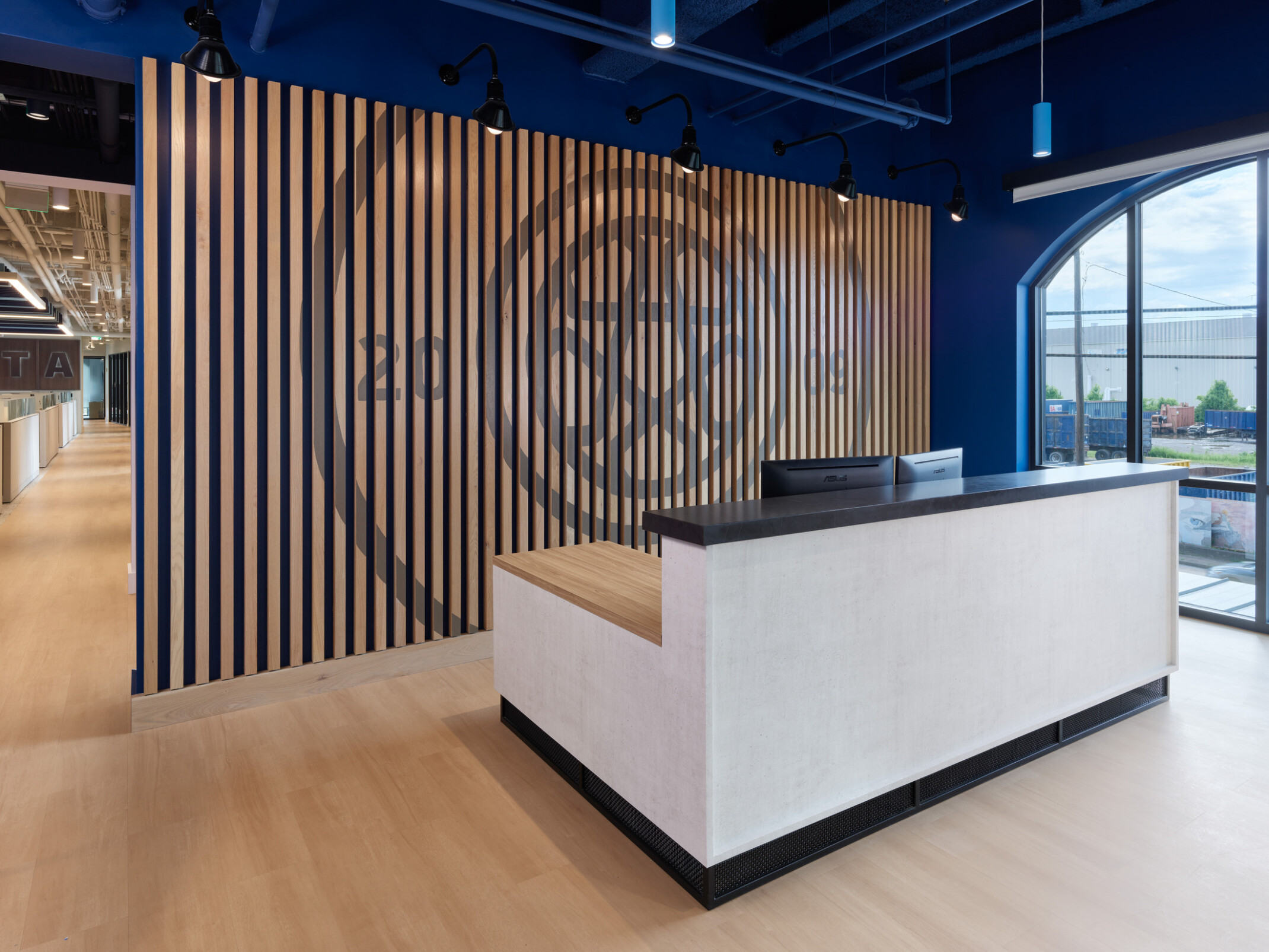 Modern reception area featuring a white reception desk, a slatted wood accent wall with a large Chattanooga Football Club logo graphic, and tall arched windows.
