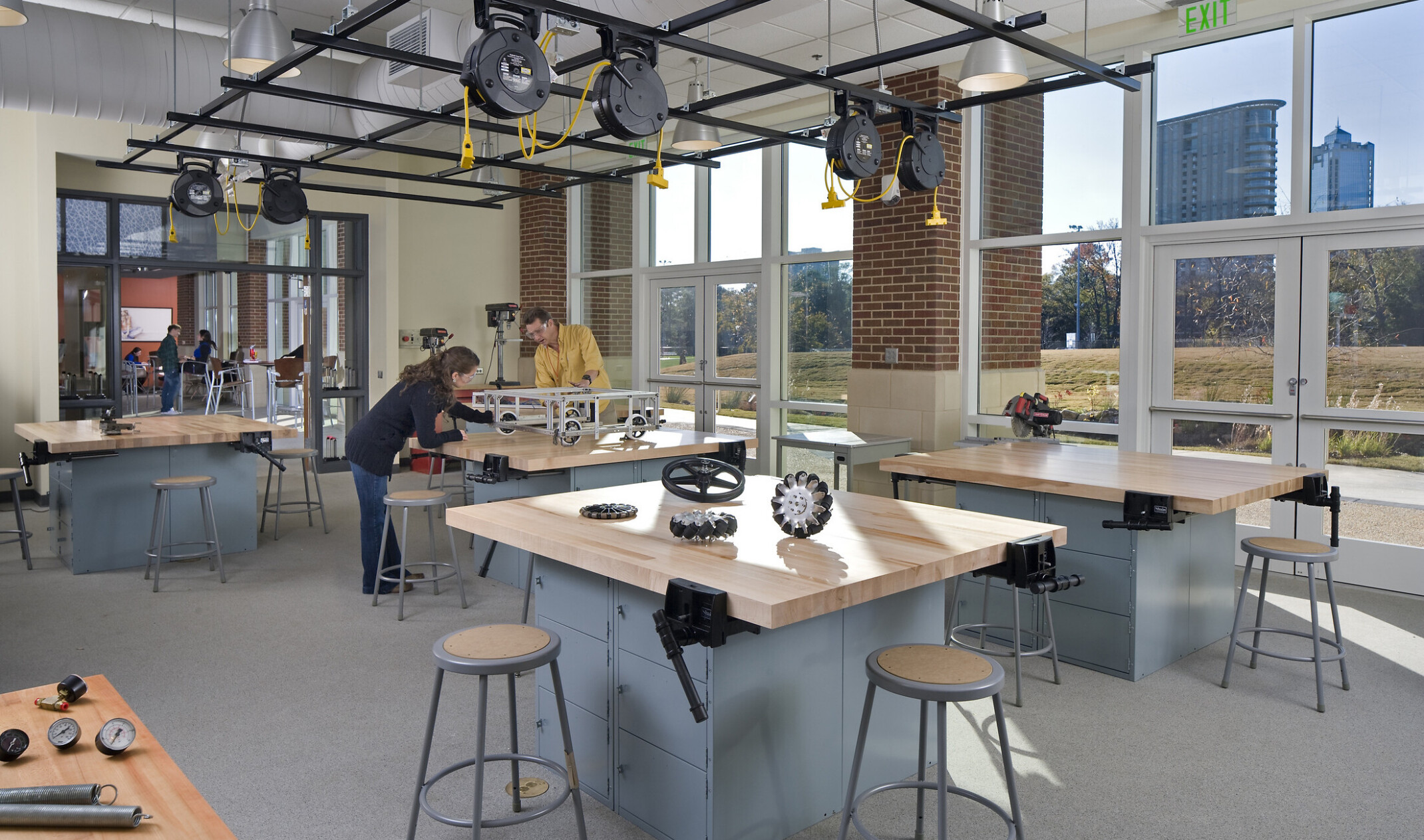 Students working in a hands-on lab space; floor to ceiling windows illuminate the workstations with wheels; mechanics, etc.