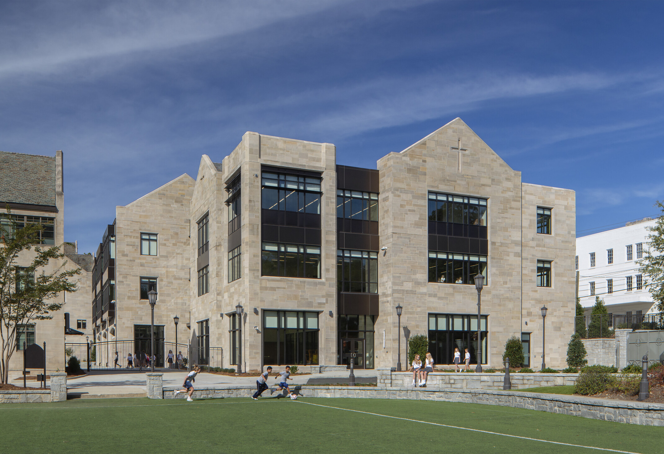 front exterior image of a modern higher education building; pavement and green courtyard for walking and sitting in the forefront of the building; multi-shaped facade