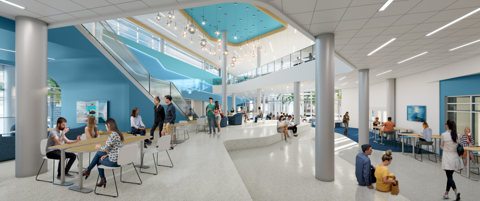 Modern high school common area filled with people sitting at tables in multiple seating arrangements around the space