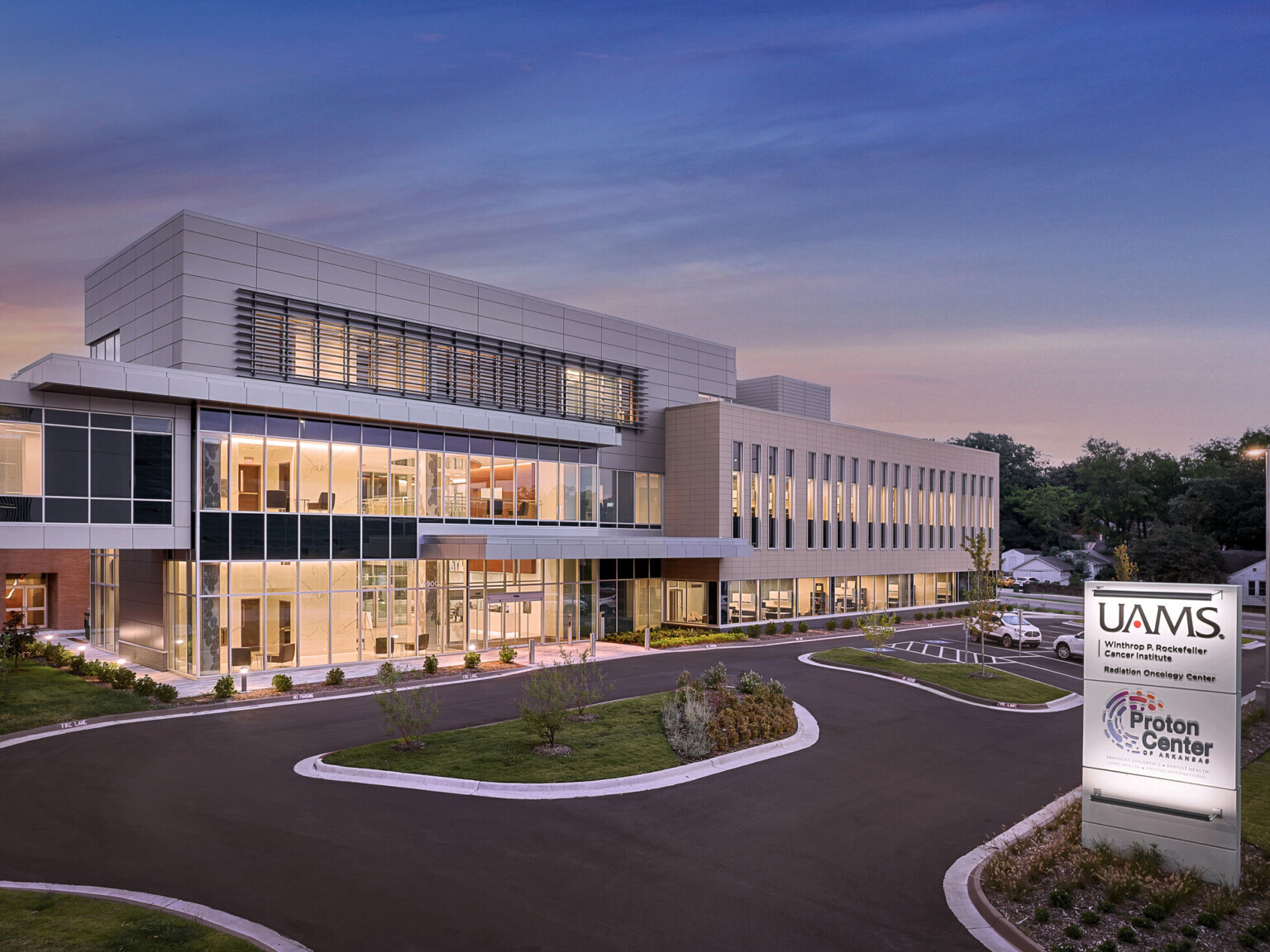 A modern, multi-story medical facility at dusk with large glass windows and a sleek design of glass and concrete.