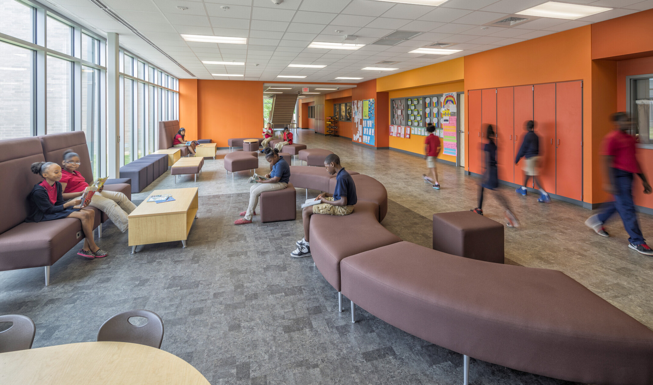 orange hallway in Boone Park Elementary School with mixed comfortable seating and floor to ceiling windows