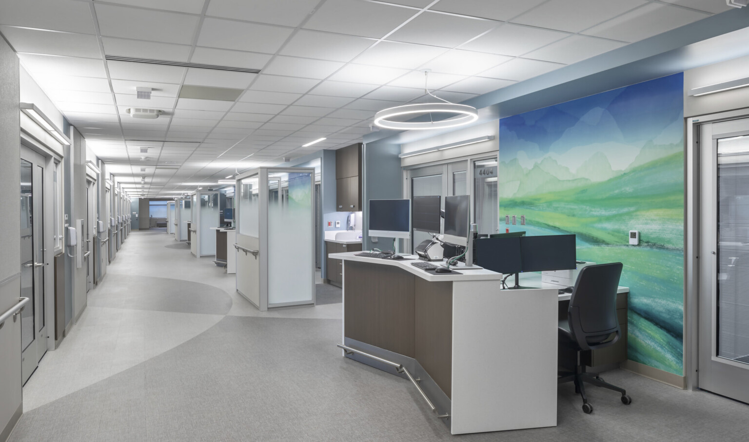 large modern artwork hung behind desk/copier station, overhead halo light, long well-lit hallway