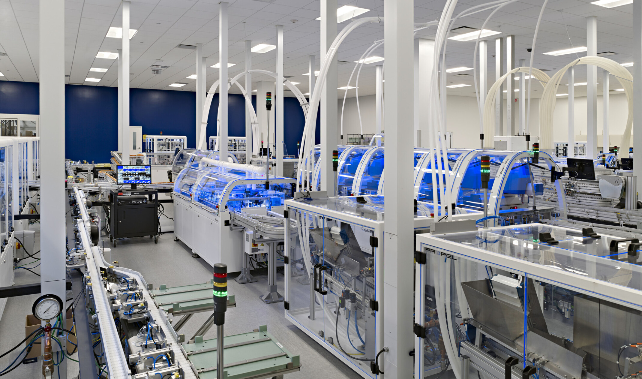 lab environment with rows of clear glass electronic manufacturing cubes with plastic tube systems connecting to the ceiling