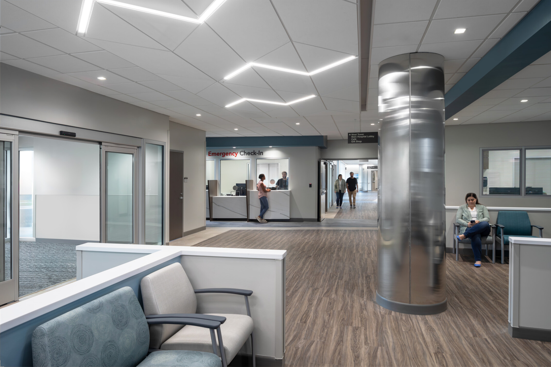 Waiting room at UNC Health Blue Ridge;s New Healthcare Pavilion; blue and white seats in the forefront with a reception desk in the back left corner; large shiny mirror like column in the middle of the room