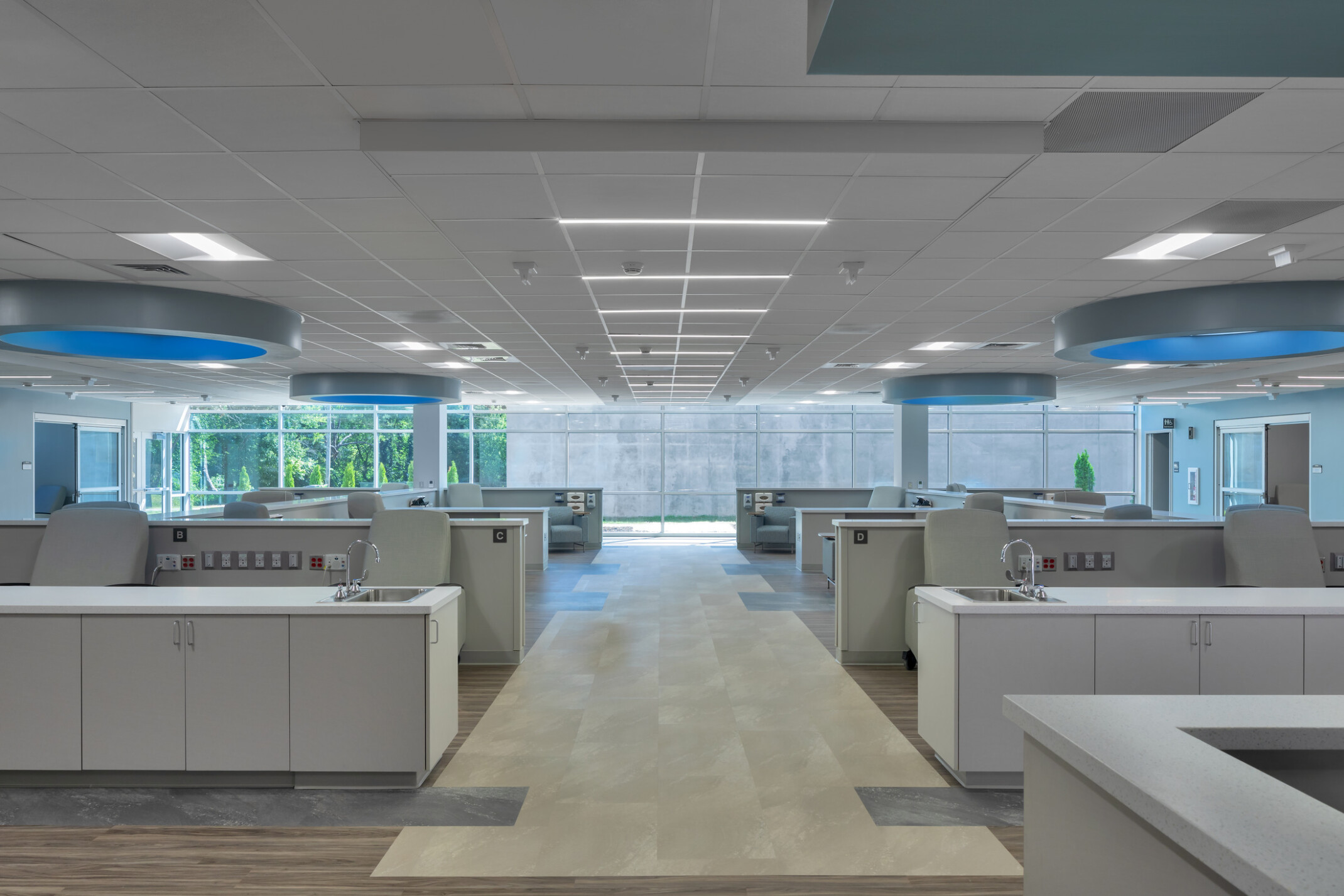 Medical office with rows of chairs with countertops and sinks with round lighting with blue glow