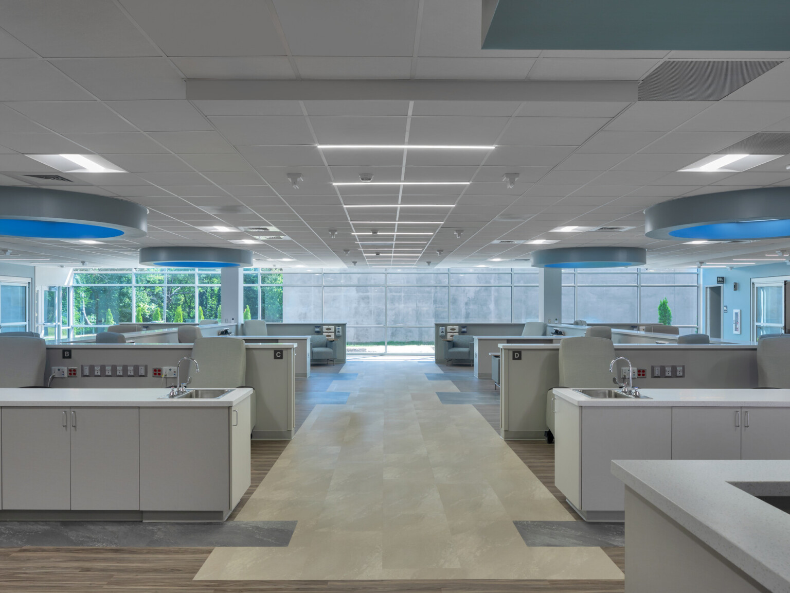 Medical office with rows of chairs with countertops and sinks with round lighting with blue glow