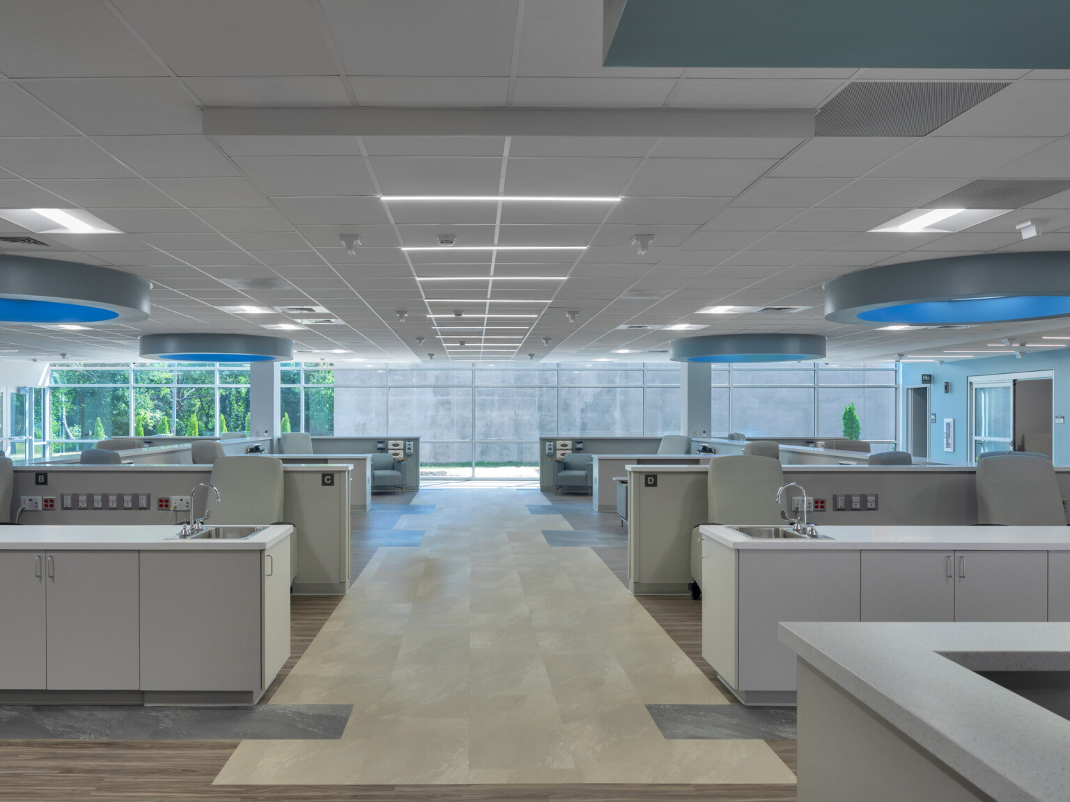 Medical office with rows of chairs with countertops and sinks with round lighting with blue glow