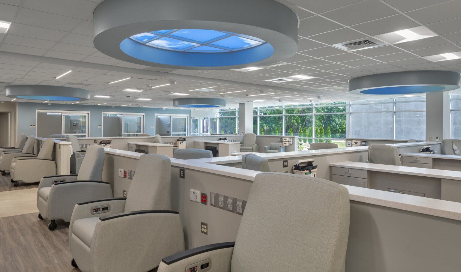 Medical office with rows of chairs with countertops and sinks with round lighting with blue glow