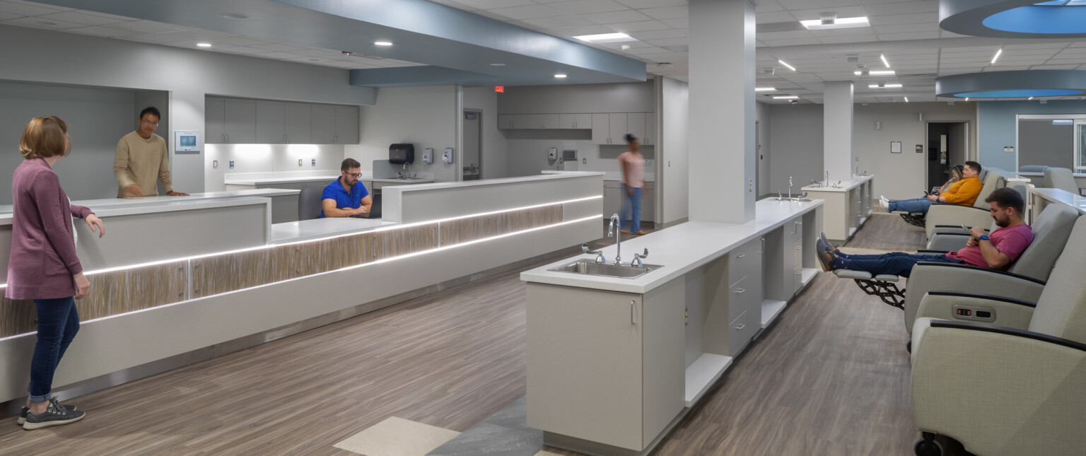 Infusion center showing patients waiting to be evaluated, circular blue light on the ceiling, and white countertops