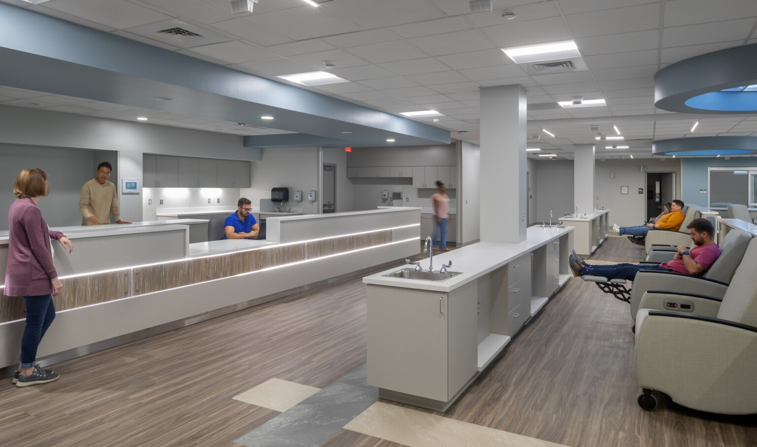 Infusion center showing patients waiting to be evaluated, circular blue light on the ceiling, and white countertops