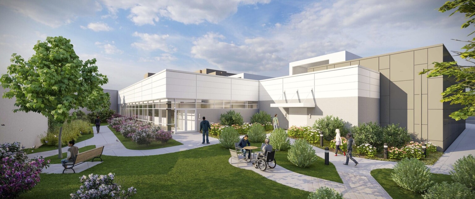 exterior rendering of UNC Health Blue Ridge Valdese Cancer Center building, people walk on courtyard pathways that lead to entrance, large windows, white building, landscaping, trees under blue skies, puffy white clouds, person in wheelchair, greenery, lawn,