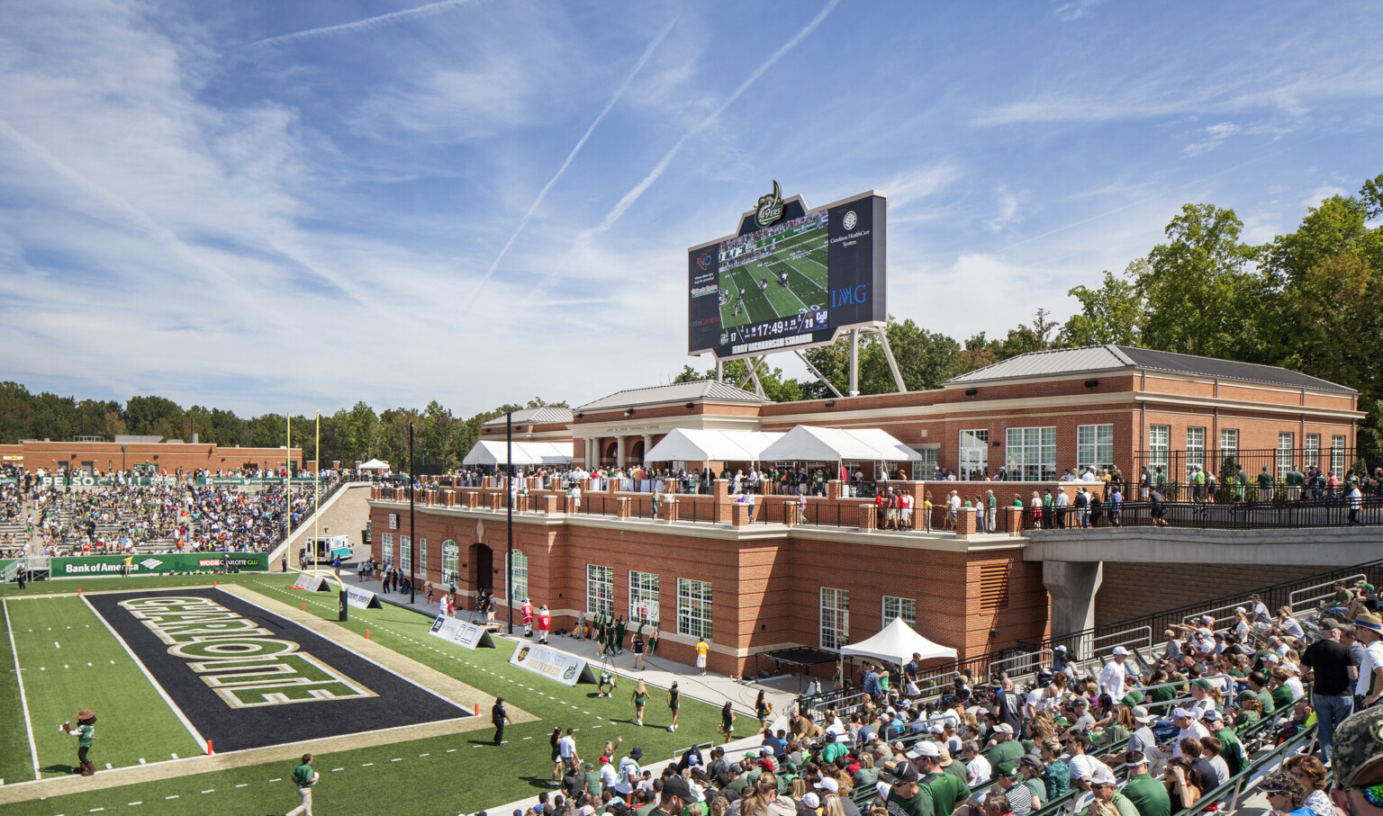 View from stands looking to brick building at end zone. 2nd floor walkway leads to patio with event space and end zone view
