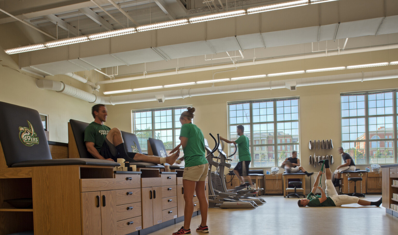 Elevated seats with wood cabinets underneath in window lined room with cardio equipment and space to stretch