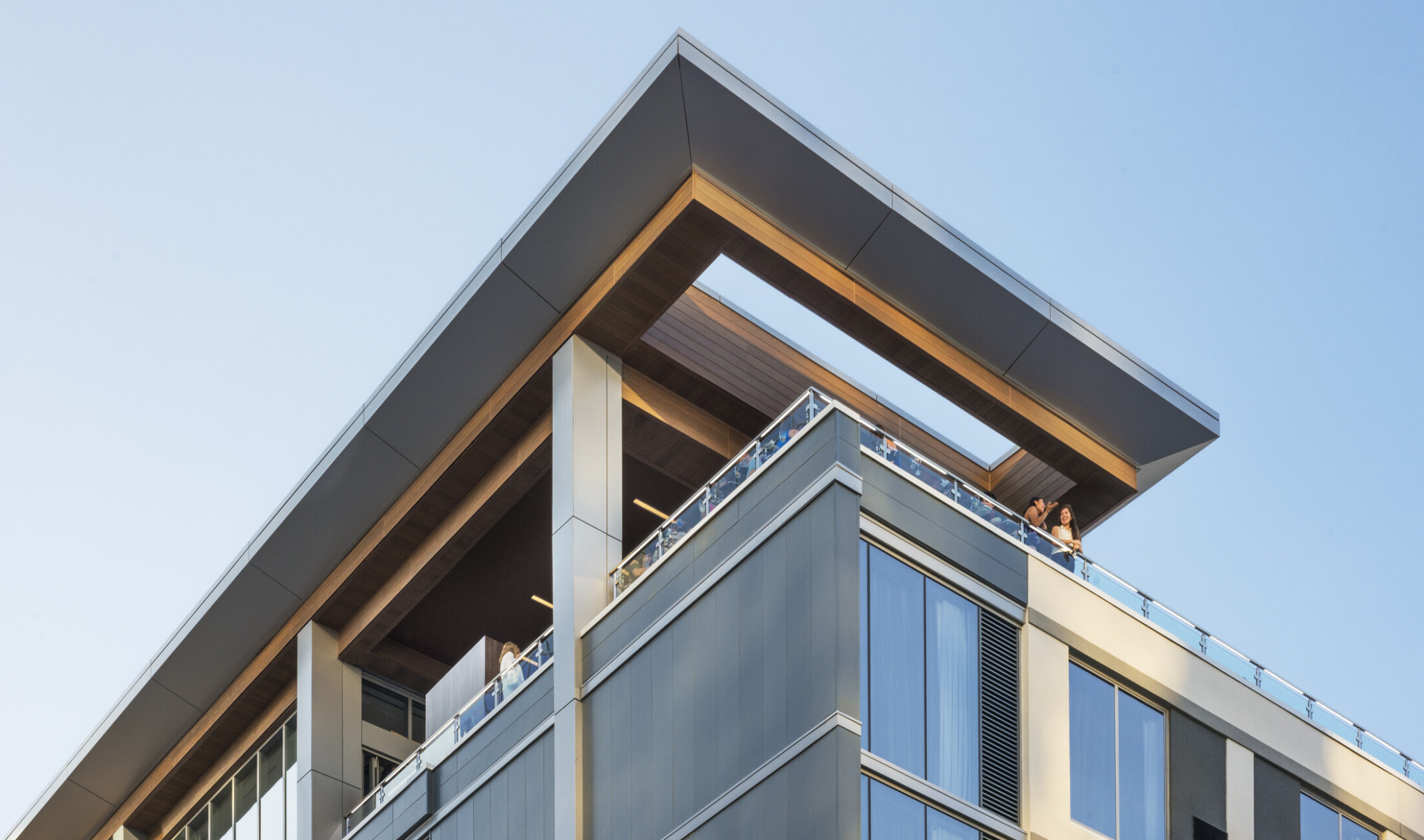 View up to corner of ac hotel in raleigh north carolina with a rooftop terrace, skylight in overhang, columns, large windows