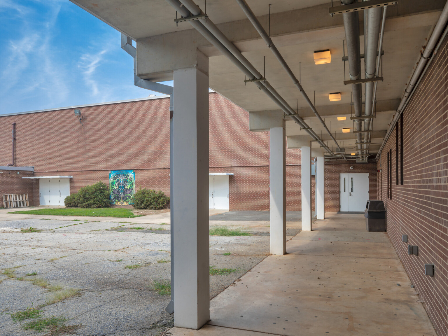 Exterior of a high school with brick walls, white doors, and a colorful mural