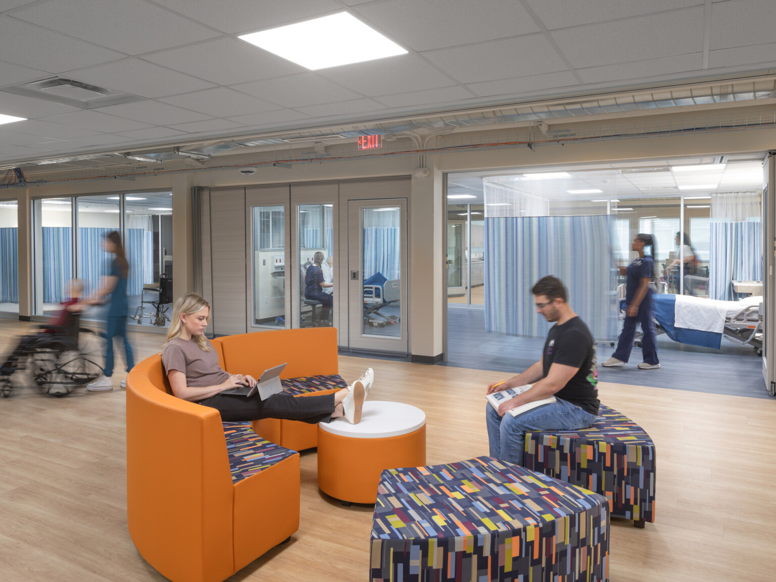 Healthcare education center showing students on modern furniture surrounded by classrooms staged as hospital rooms