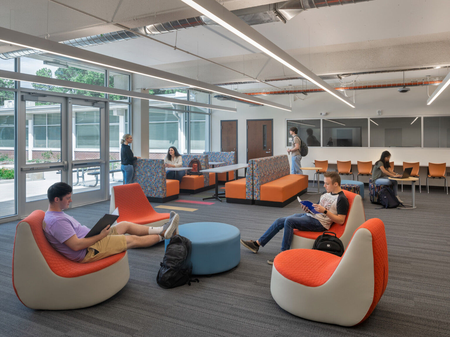 High school study area with modern furniture filled with students interacting and working on computers