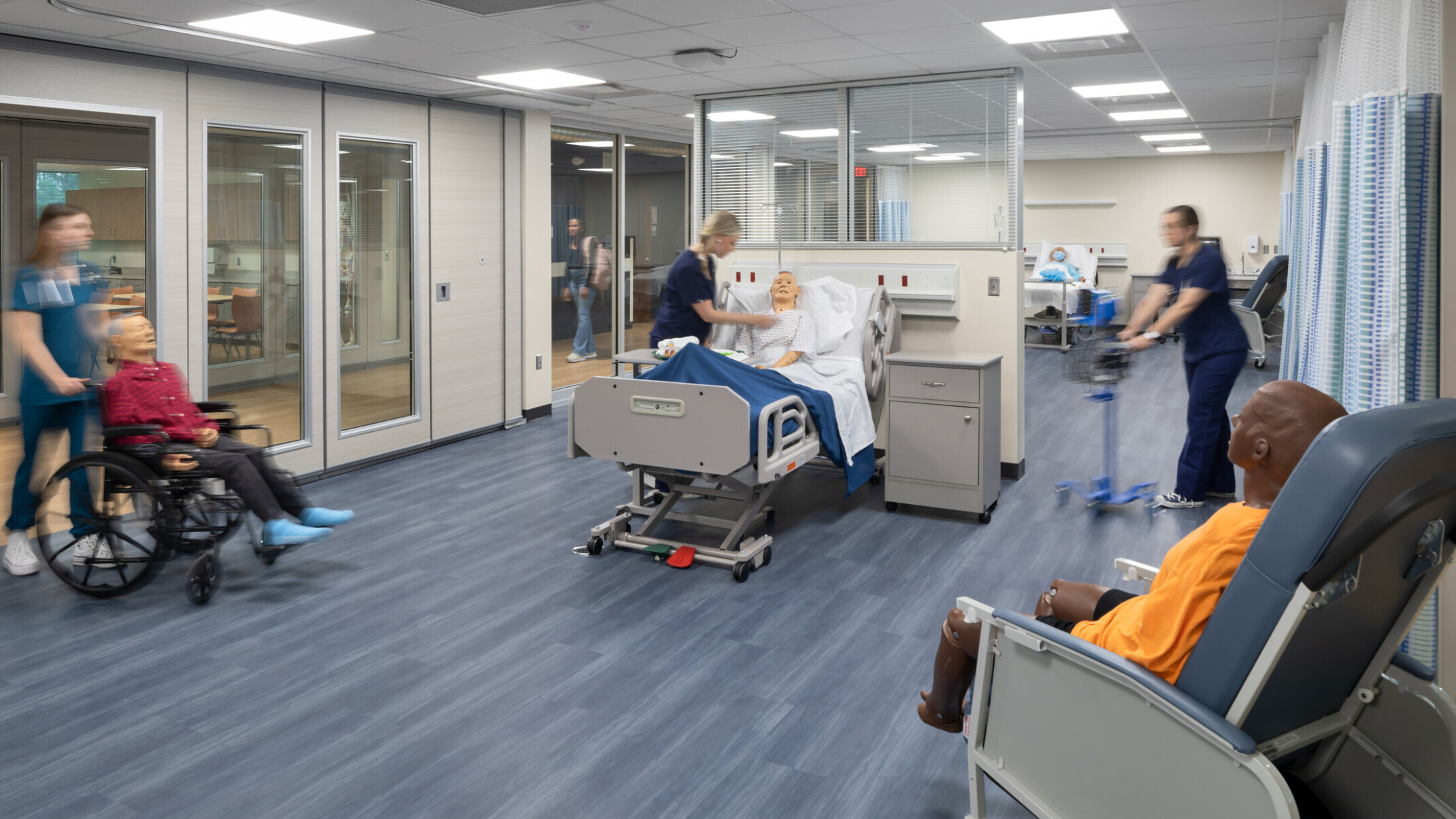 Healthcare education center showing students working on mock patients in hospital beds