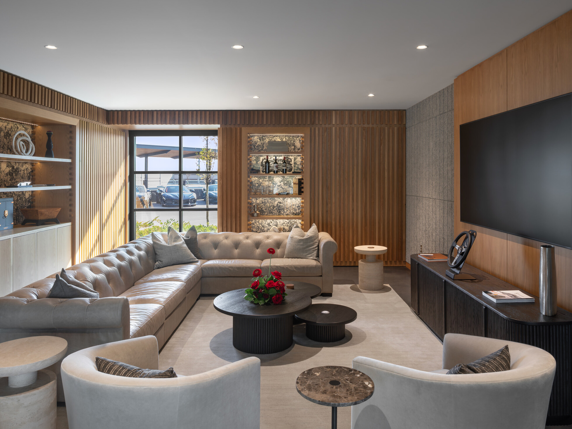modern luxury space with sofa and chairs facing a large screen on right wall; overlooking race track