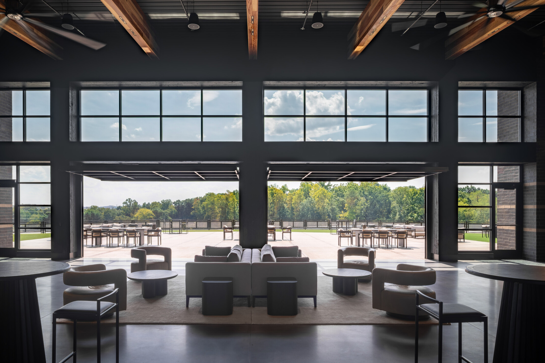 open concept lounge space with modular seating facing floor to ceiling windows and entries