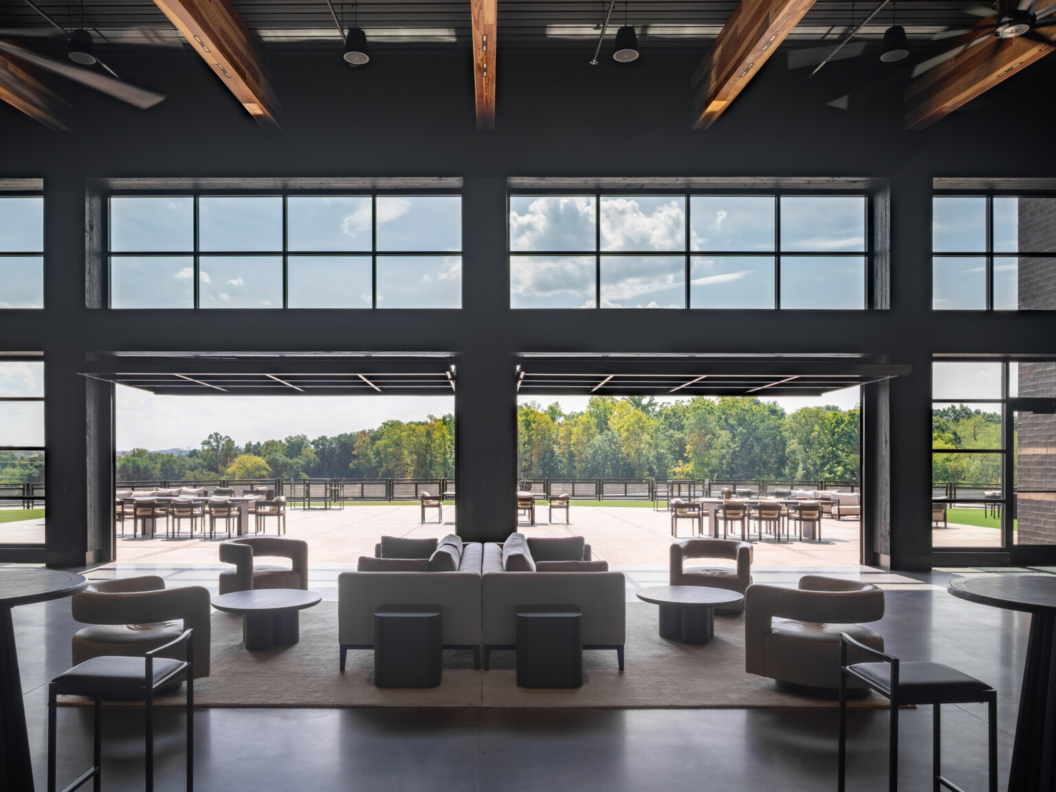 open concept lounge space with modular seating facing floor to ceiling windows and entries