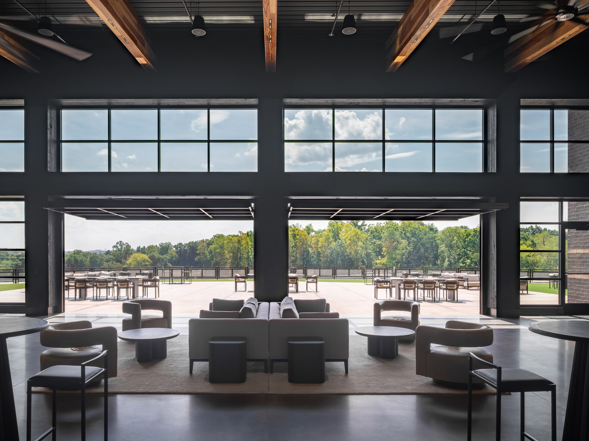 open concept lounge space with modular seating facing floor to ceiling windows and entries