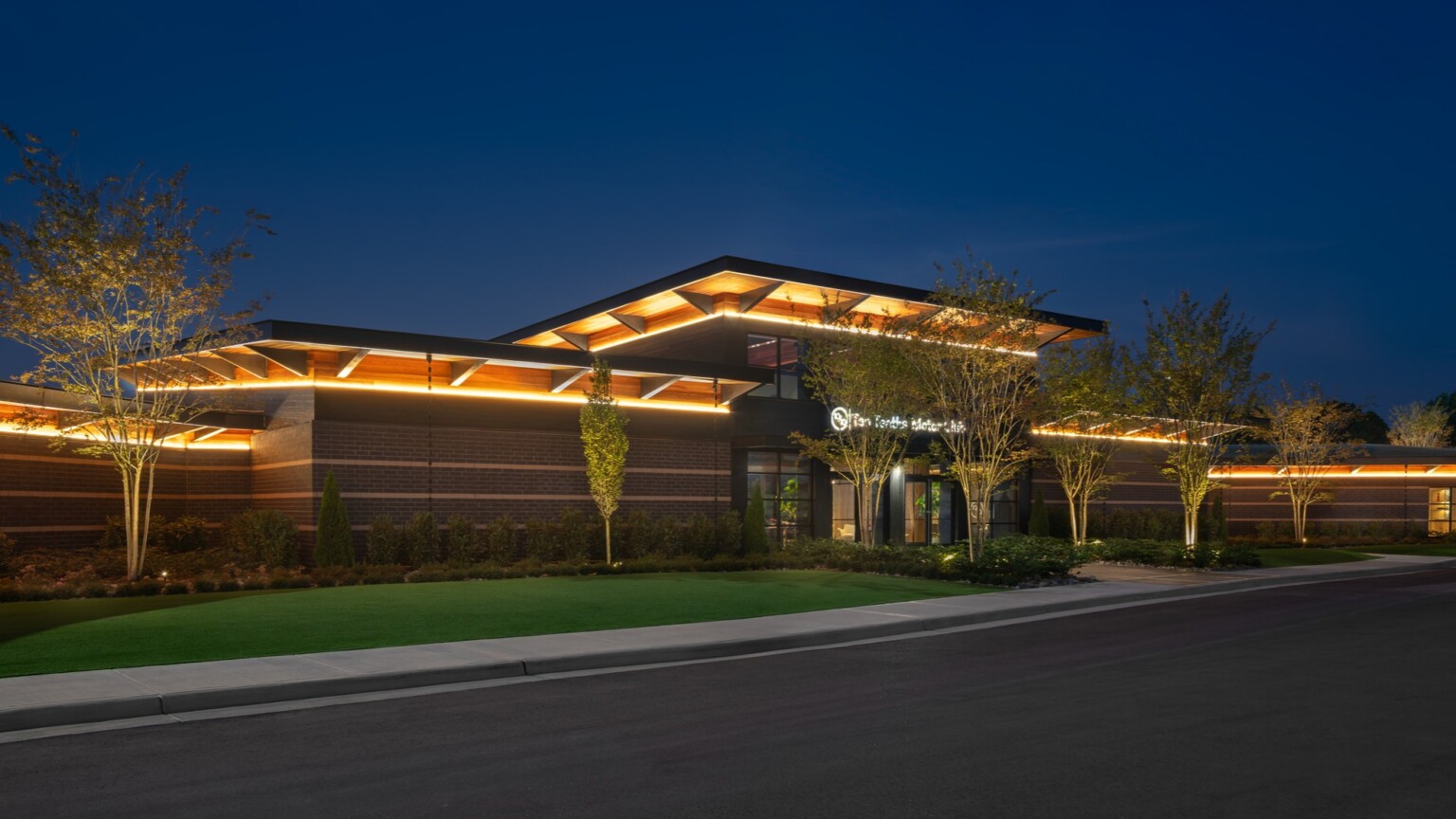 nighttime exterior of Ten Tenths Clubhouse; black exterior brick with a mass timber awning