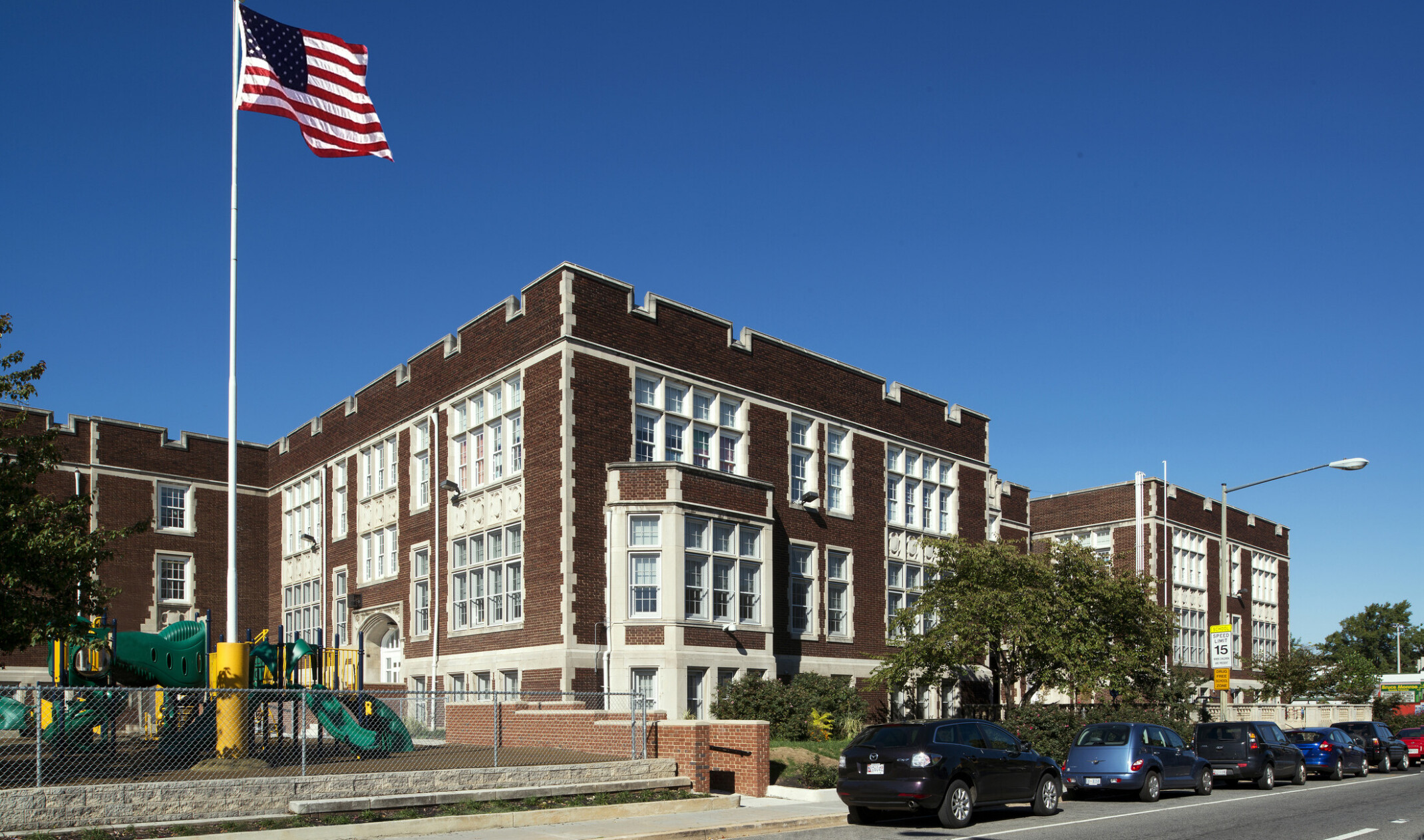 exterior image of a cube brick building with white paneling accents on the windows; forefront US flag on pole