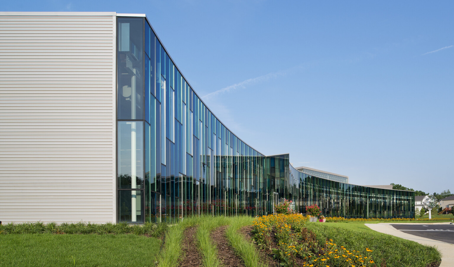 Curved building with glass facade reflecting the sky and surroundings.