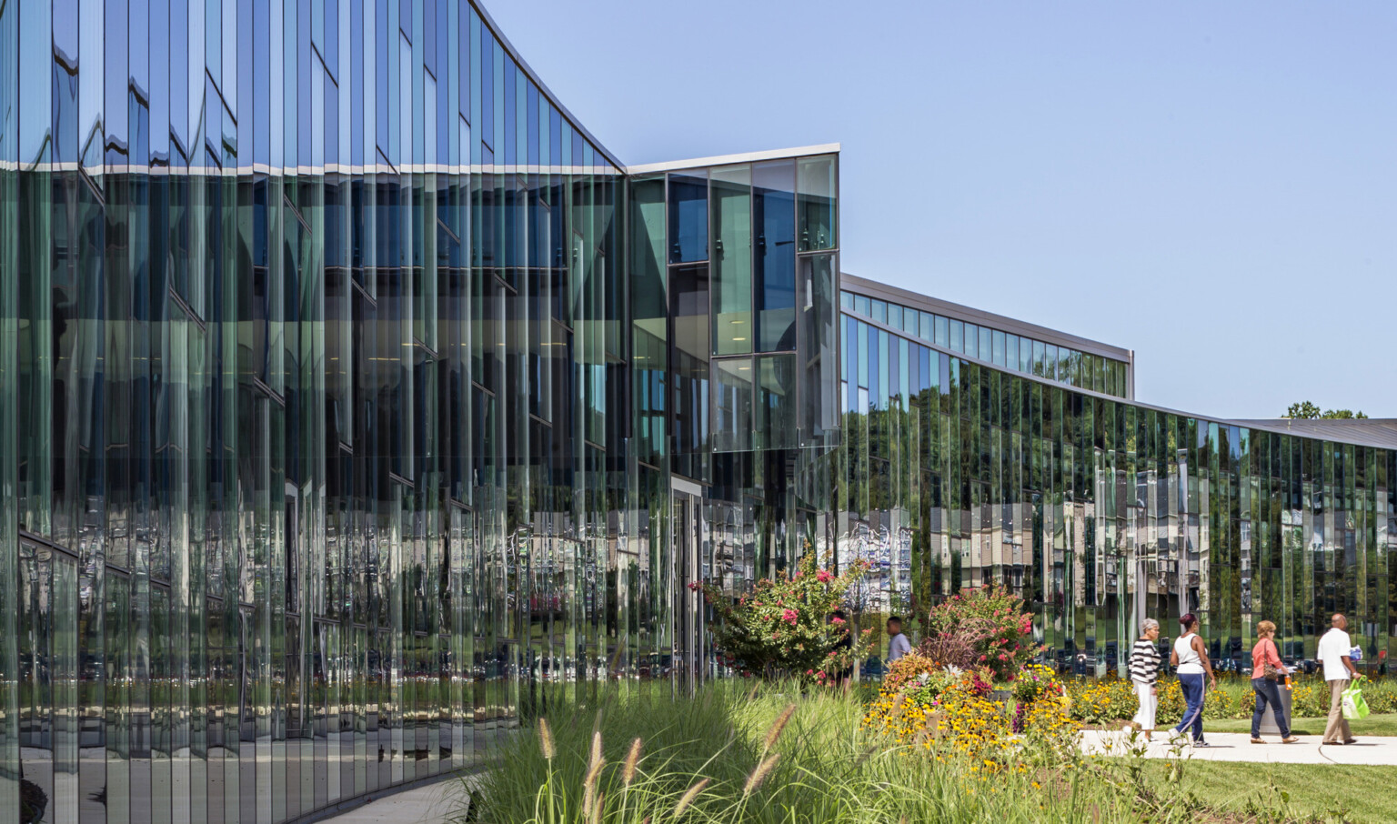 Curved building with glass facade reflecting the sky and surroundings.