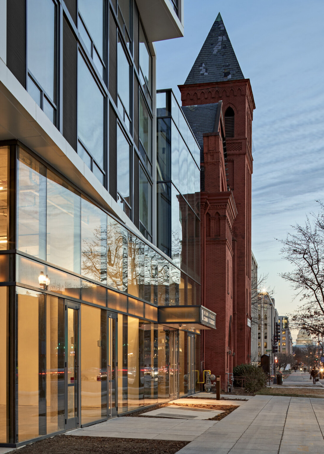 Sidewalk with modern glass windows to the left looking down a street lined with buildings