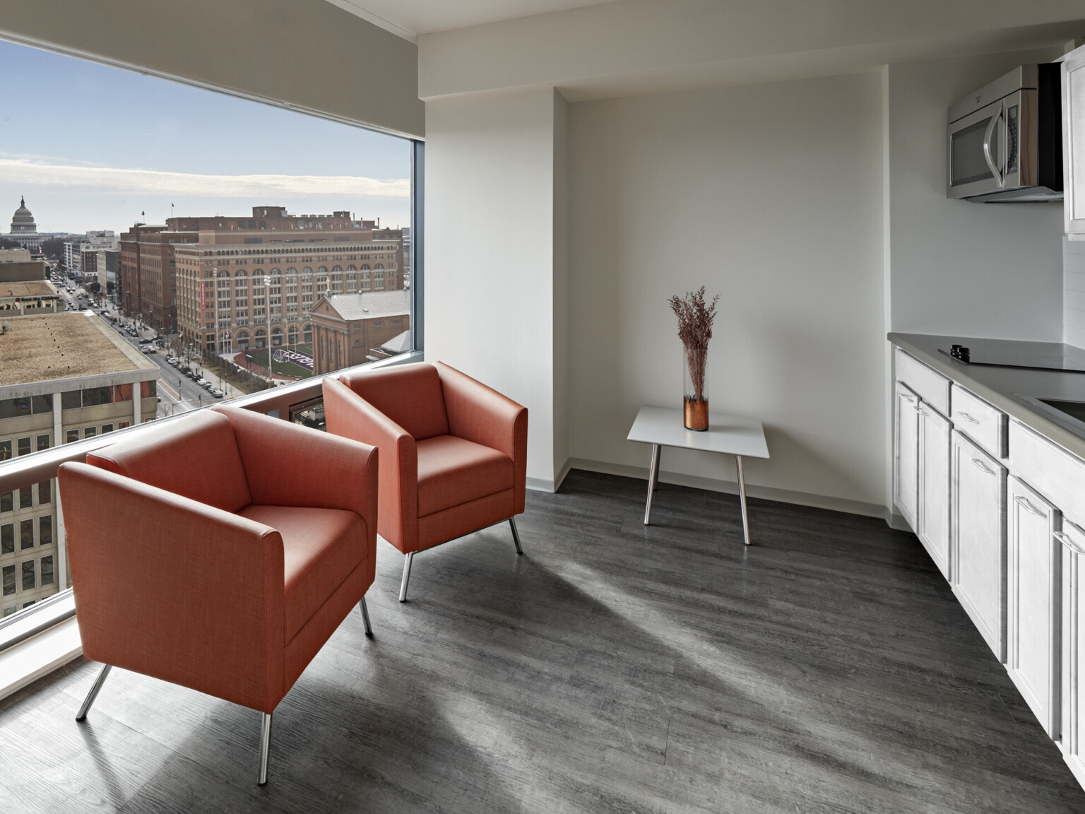 Red modern chairs in a room with white cabinetry and grey floors showcasing a large window