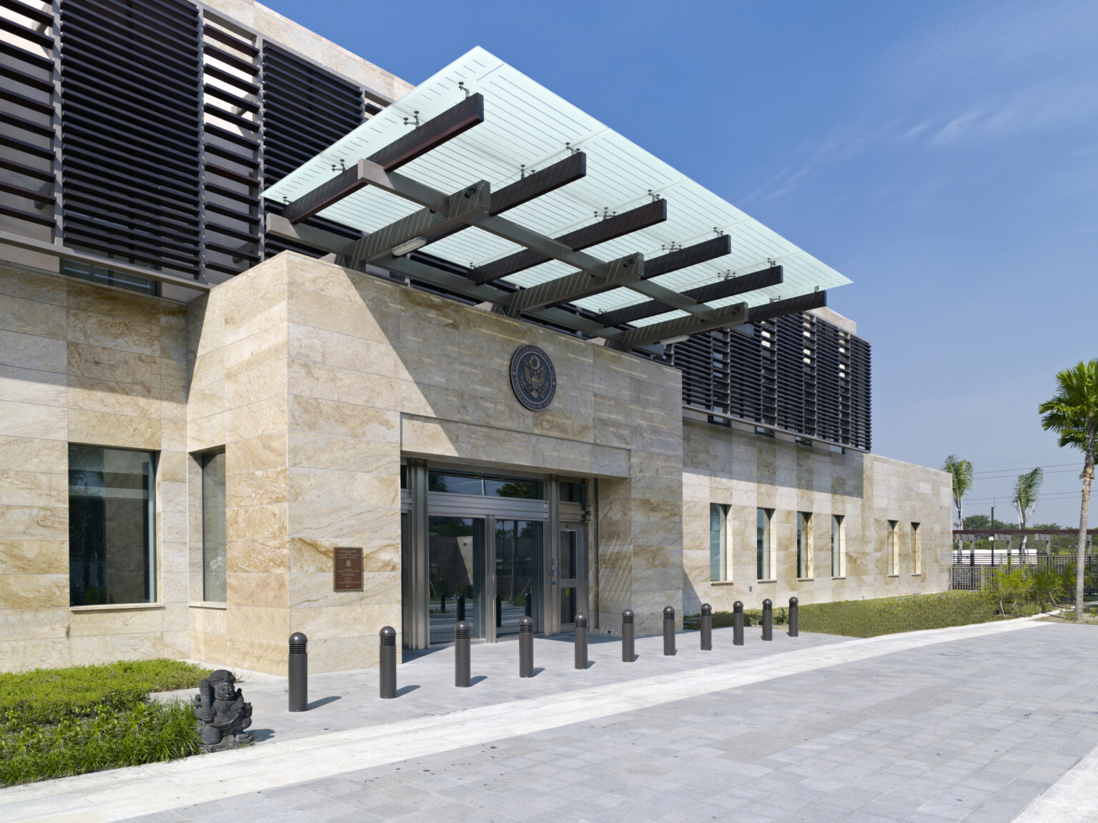 Exterior entrance of U.S. Consulate General, Surabaya, Indonesia. Off white tile exterior with metal louvered awnings Exterior entrance of U.S. Consulate General, Surabaya, Indonesia. Off white tile exterior with metal louvered awnings