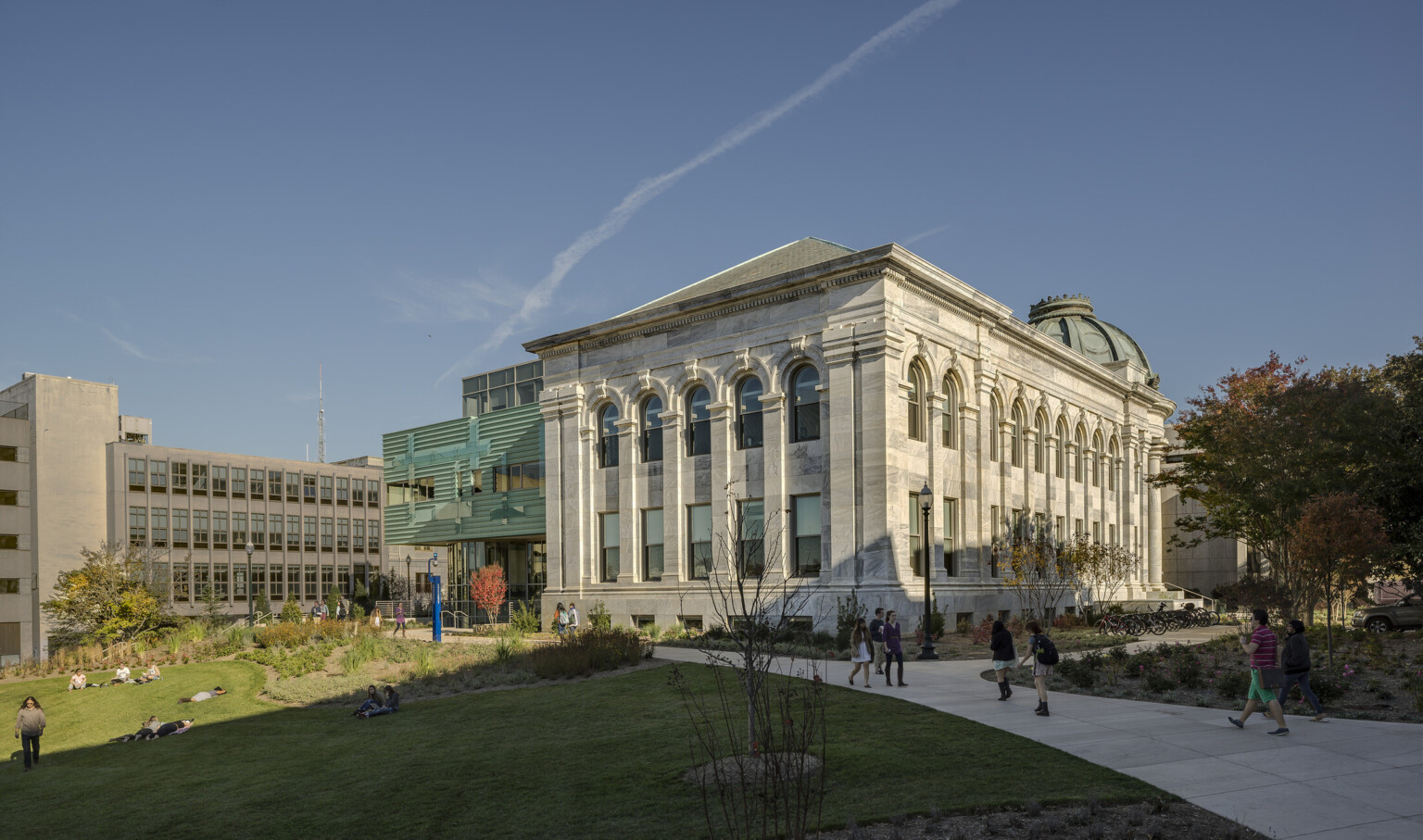 neoclassical stone building with arched windows, inset columns, domed rotunda, modern glass and green facade addition