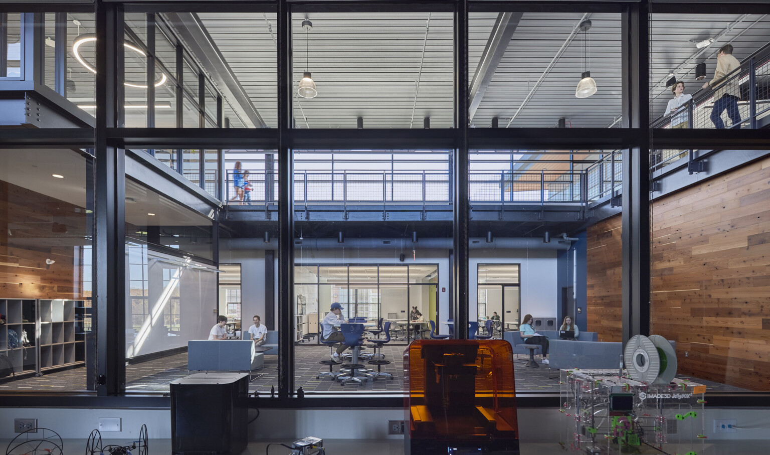 learning atrium surrounded by an elevated walkway built out of black steal, robotics equipment in view