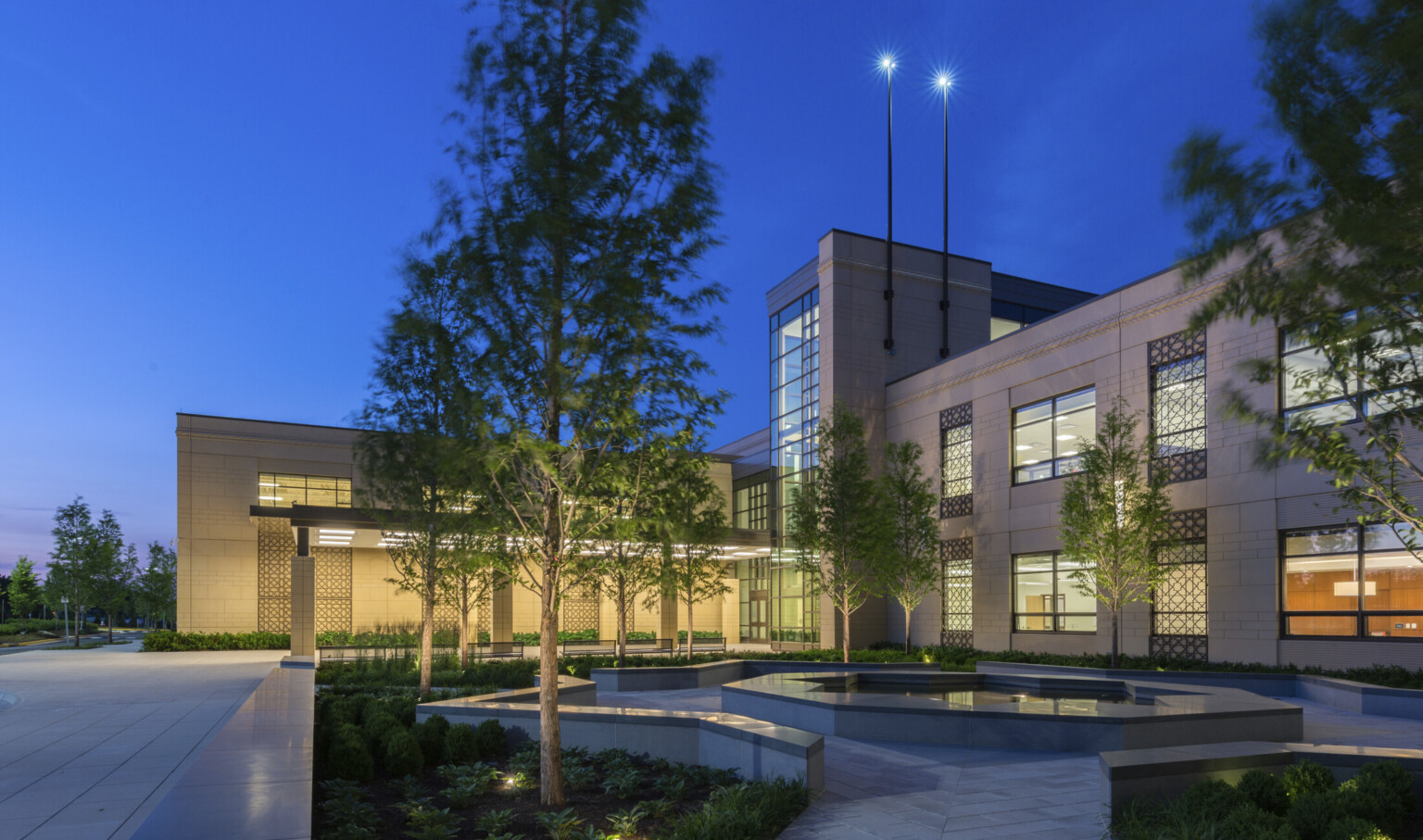 nighttime view of a school built with precast concrete façade, an illuminated canopy entrance leads to a double-height glass atrium