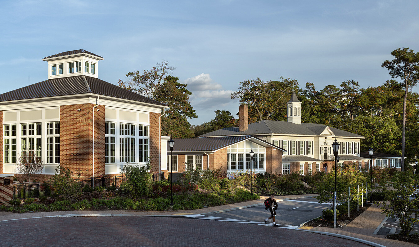 federal style brick buildings with black metal roof white trim and windows with white mullions along tree lined concrete path