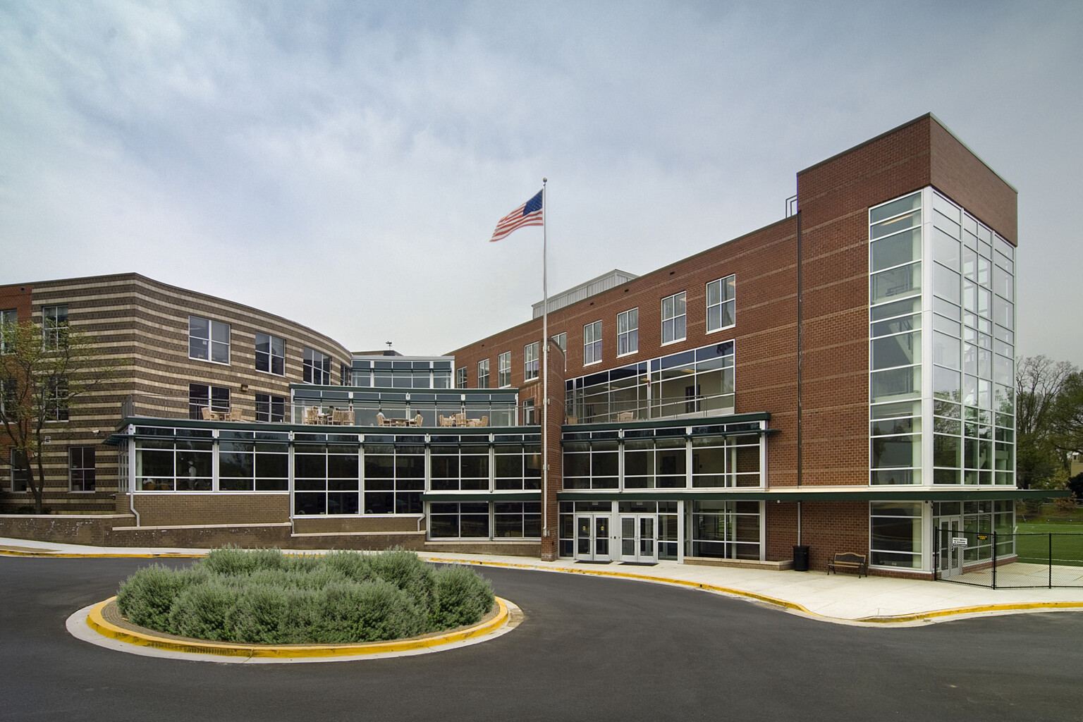 Exterior of Georgetown Day School Athletic Center showing a multistory building filled with windows with the American flag on a flagpole out front