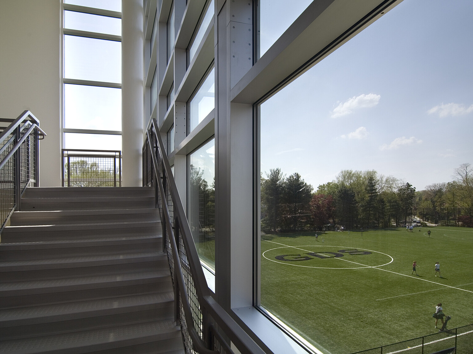 Stairway with floor to ceiling windows to the right overlooking a soccer field
