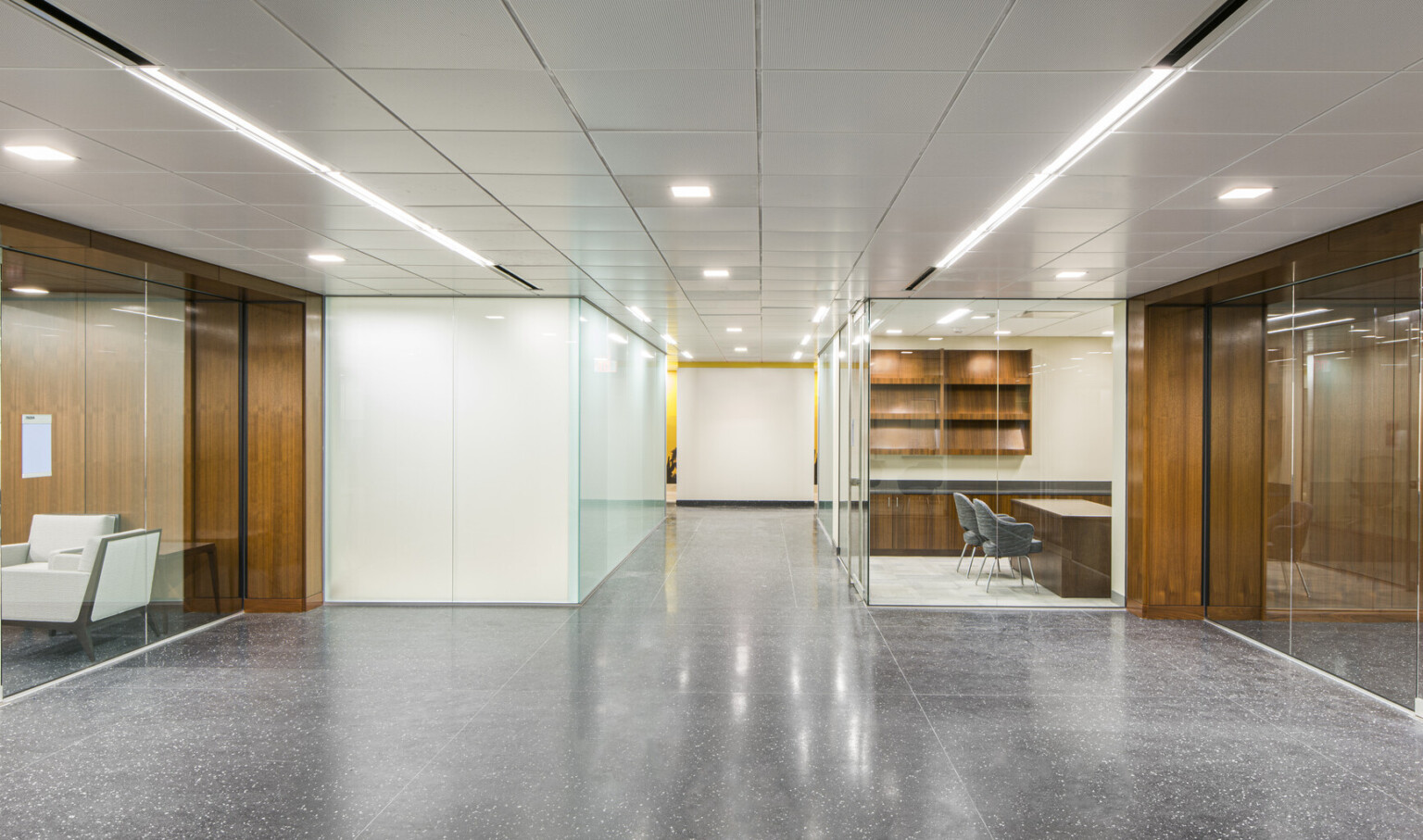 Interior hallway in the GSA Harry S. Truman Federal building with white walls and wood details. Glass offices to either side