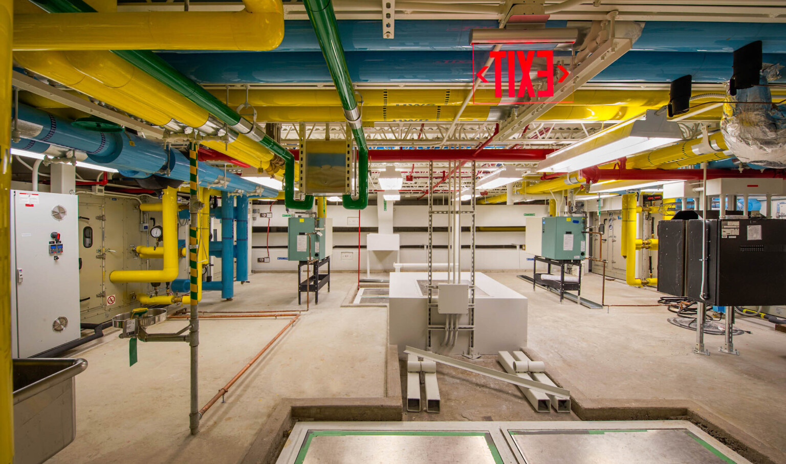 Colorful exposed pipes in white room with mechanical boxes