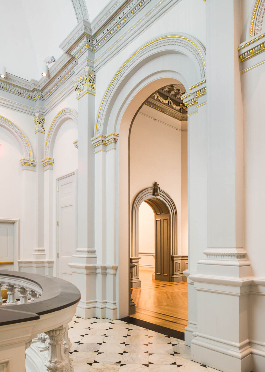 Custom sculptural chandelier hanging above staircase in white room at Renwick Gallery, banister with dark accent in front