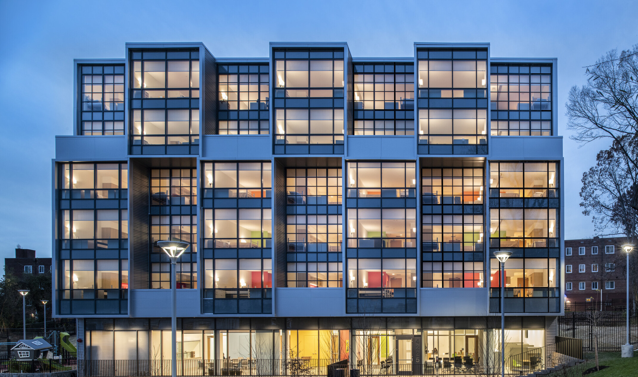 Exterior view of a section the Triumph with window covered facade illuminated at night with interior rooms visible