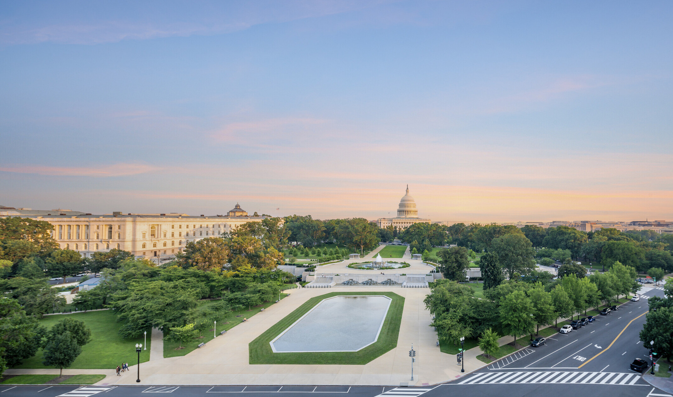 Wide shot of reflection pool with the Capitol building in the background against a sunset sky.