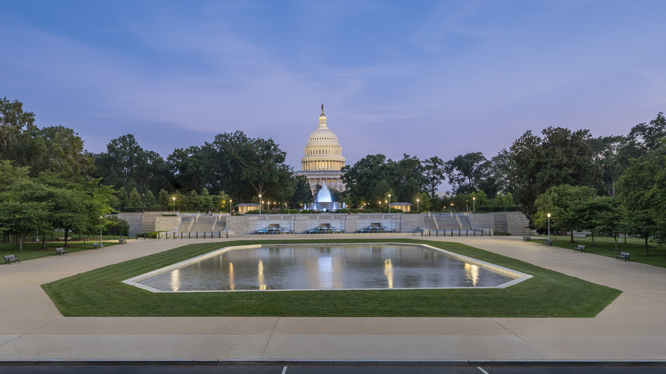 Wide shot of reflection pool with the Capitol building in the background against a sunset sky.